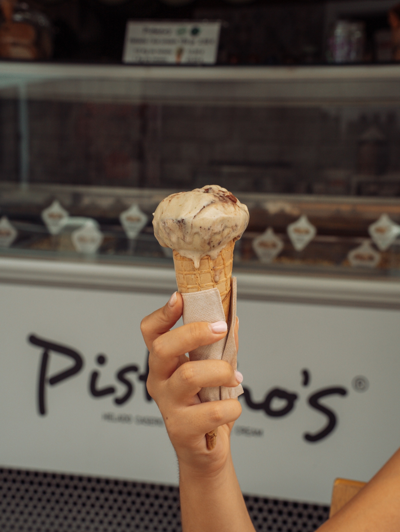 Pistacho's cone held in front of the store